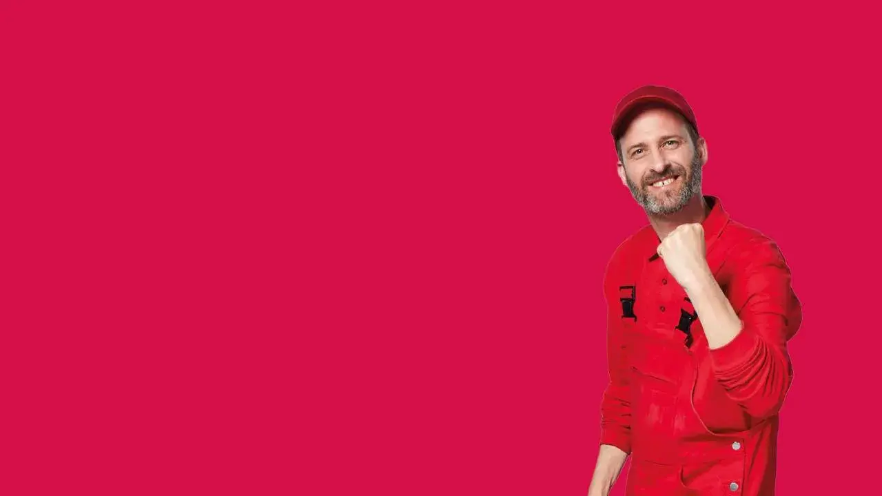 Bärtiger Mann in roter Arbeitskleidung mit motivierender Geste vor neutralem Hintergrund in magenta